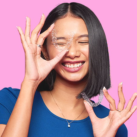 A smiling Zenyum user enthusiastically holding a pair of Zenyum Invisible Braces